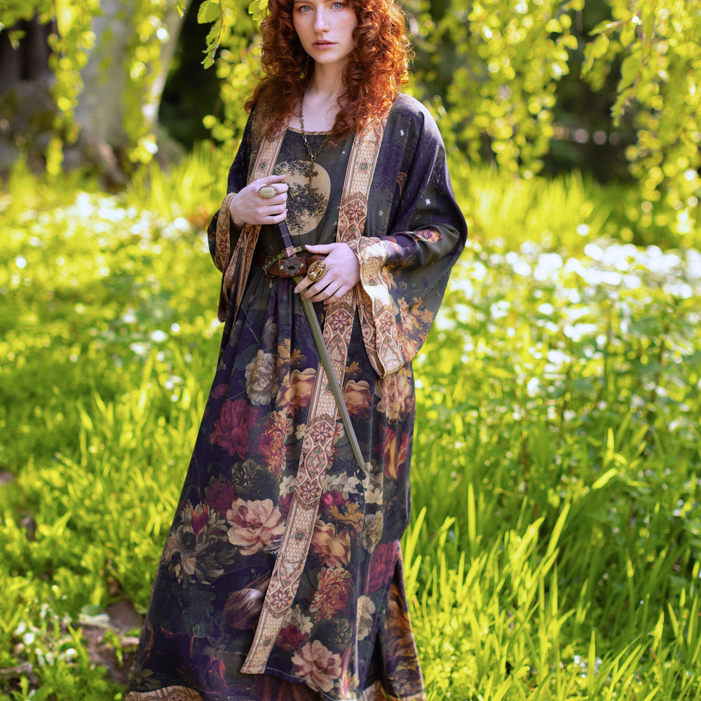 
                  
                    Model wearing a maxi-length bamboo-viscose slip dress featuring florals from centuries-old paintings and Rosetti’s iconic portrait of Joan of Arc - Market of Stars
                  
                