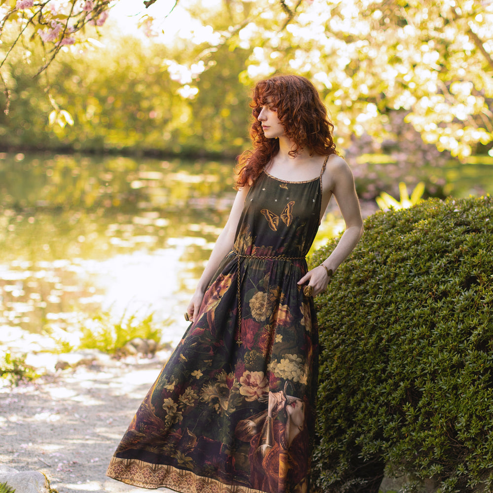 
                  
                    Model wearing a maxi-length bamboo-viscose slip dress featuring florals from centuries-old paintings and Rosetti’s iconic portrait of Joan of Arc - Market of Stars
                  
                