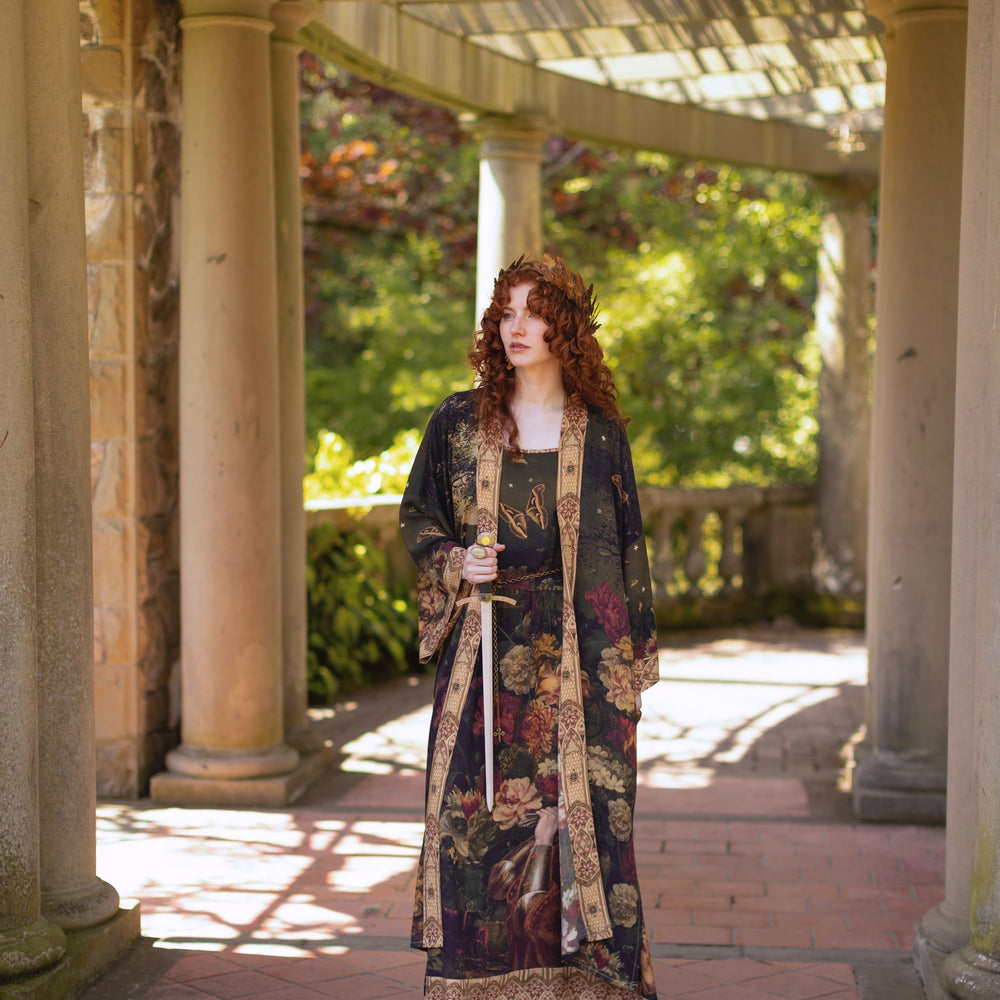 
                  
                    Model wearing a maxi-length bamboo-viscose slip dress featuring florals from centuries-old paintings and Rosetti’s iconic portrait of Joan of Arc - Market of Stars
                  
                