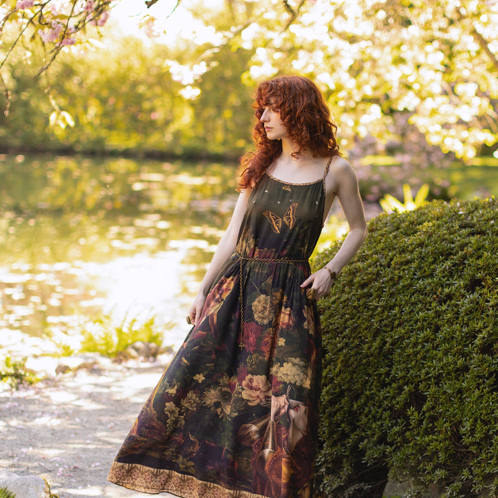 
                  
                    Model wearing a maxi-length bamboo-viscose slip dress featuring florals from centuries-old paintings and Rosetti’s iconic portrait of Joan of Arc - Market of Stars
                  
                