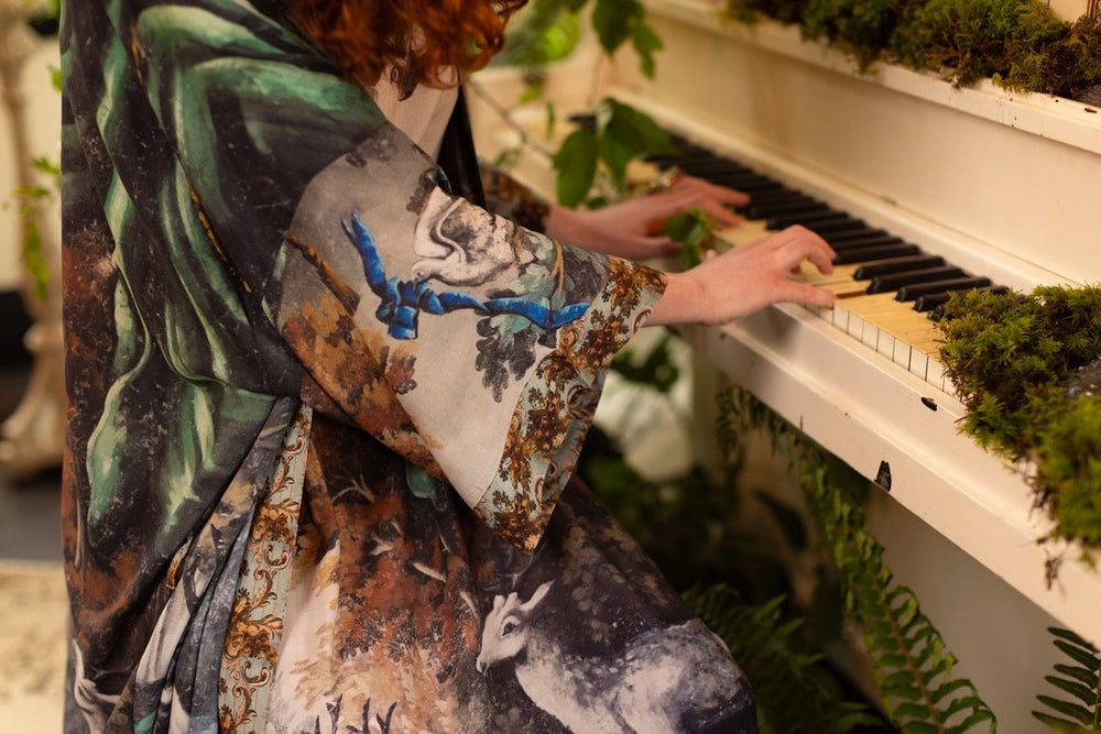 
                  
                    Model wearing the Theatre of Dreams Opera Duster featuring whimsical birds, love letters, and richly painted curtains by artist Jennifer Lanne – Market of Stars
                  
                