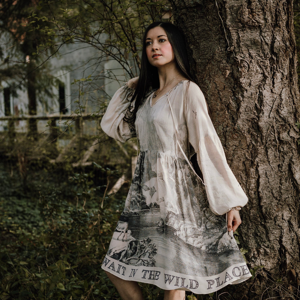 Model wearing knee-length dress with long sleeves featuring vintage print of a forest, songbirds and sunshine - Market of Stars