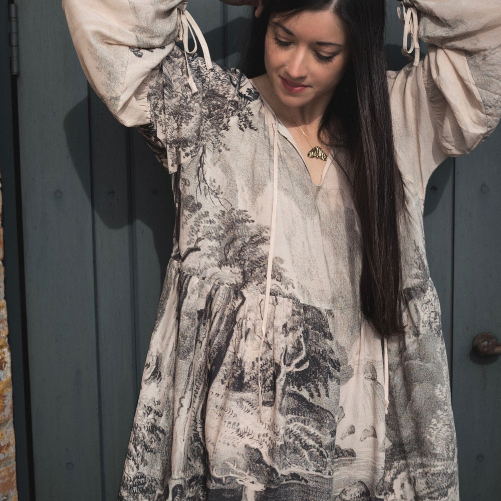 Model wearing knee-length dress with long sleeves featuring vintage print of a forest, songbirds and sunshine - Market of Stars