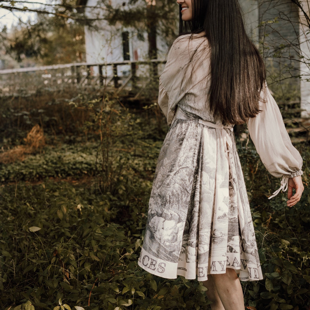 
                  
                    Model wearing knee-length dress with long sleeves featuring vintage print of a forest, songbirds and sunshine - Market of Stars
                  
                