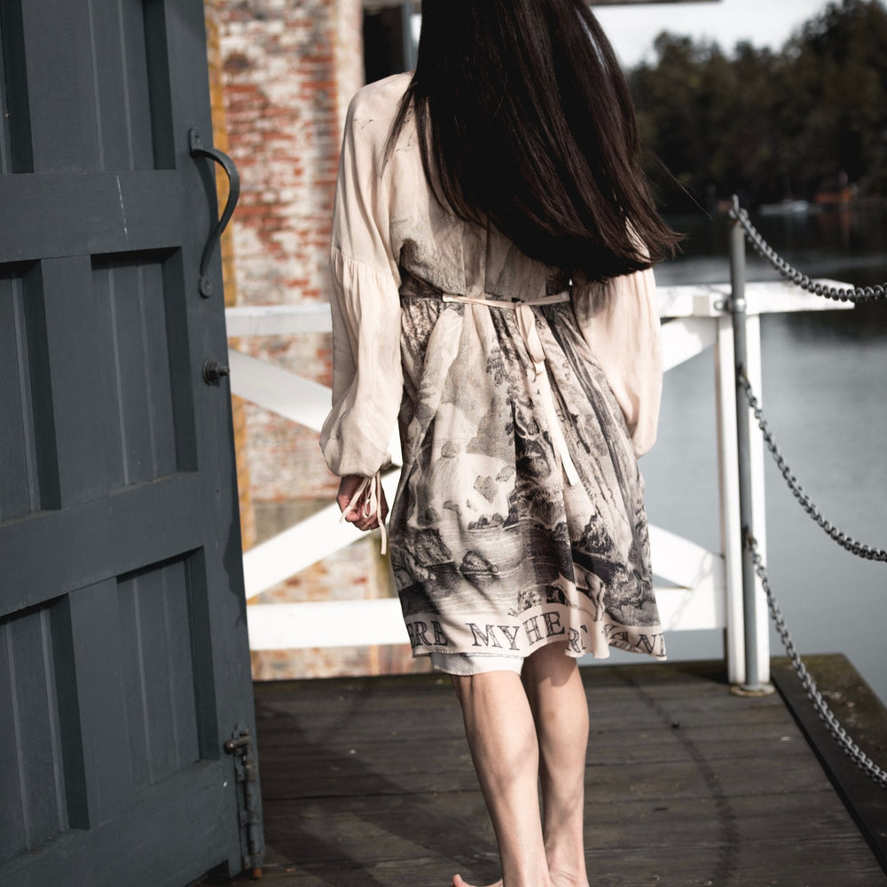 
                  
                    Model wearing knee-length dress with long sleeves featuring vintage print of a forest, songbirds and sunshine - Market of Stars
                  
                