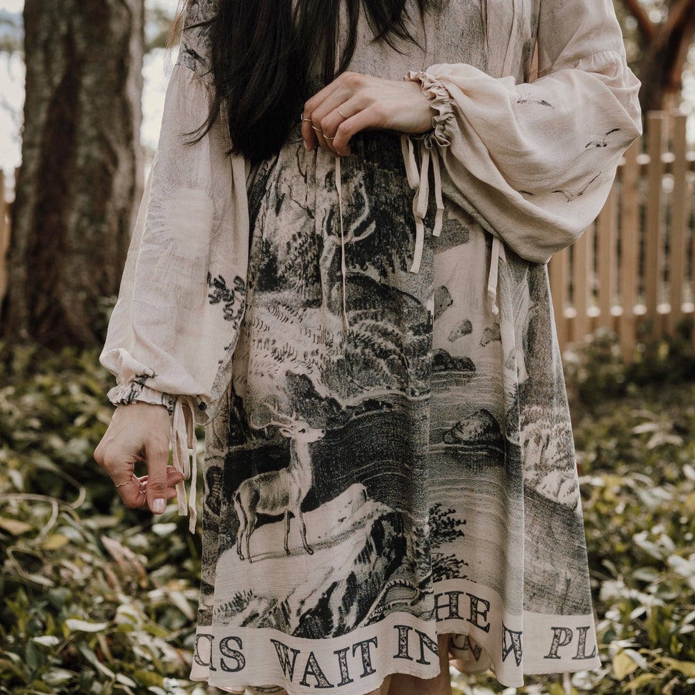 
                  
                    Model wearing knee-length dress with long sleeves featuring vintage print of a forest, songbirds and sunshine - Market of Stars
                  
                