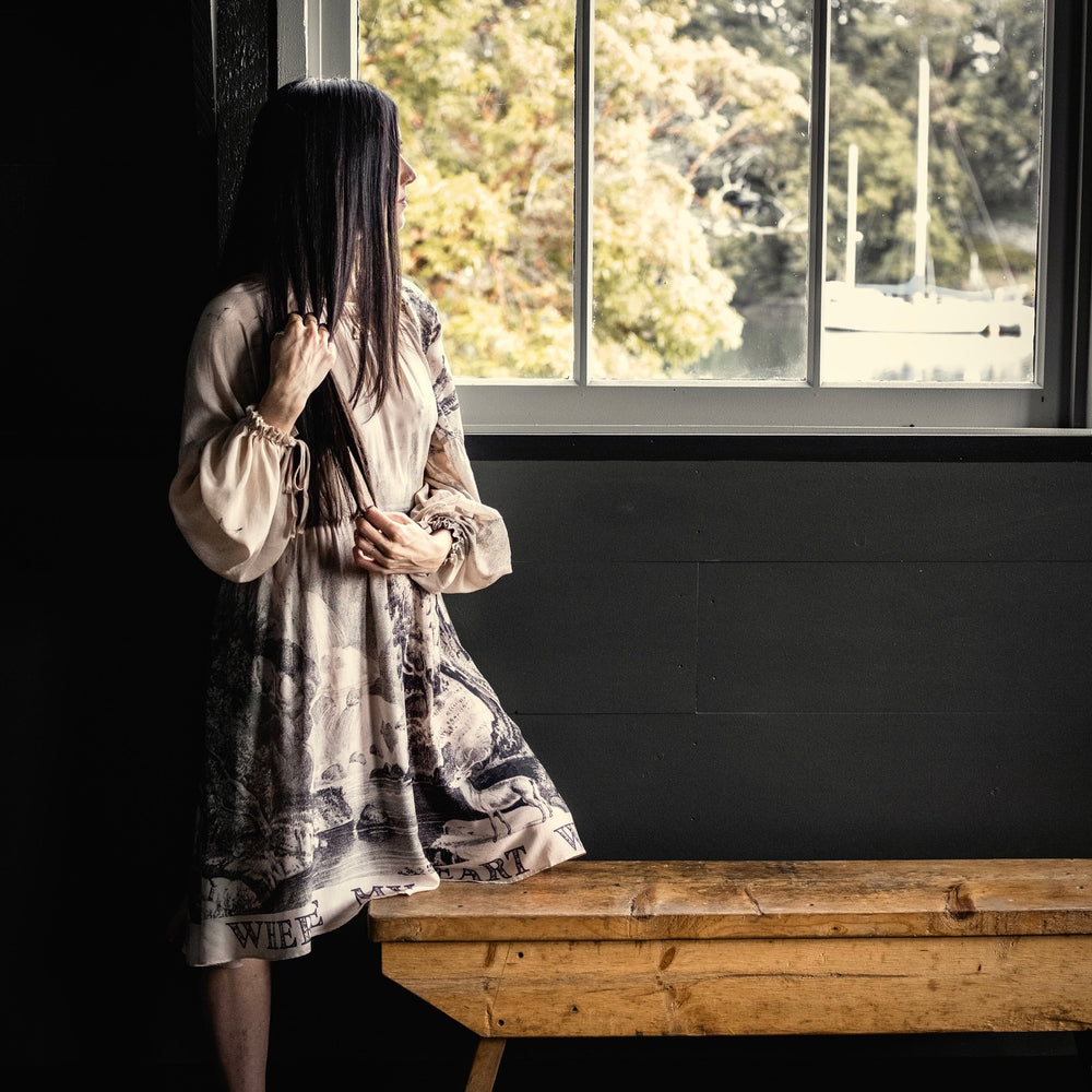 
                  
                    Model wearing knee-length dress with long sleeves featuring vintage print of a forest, songbirds and sunshine - Market of Stars
                  
                