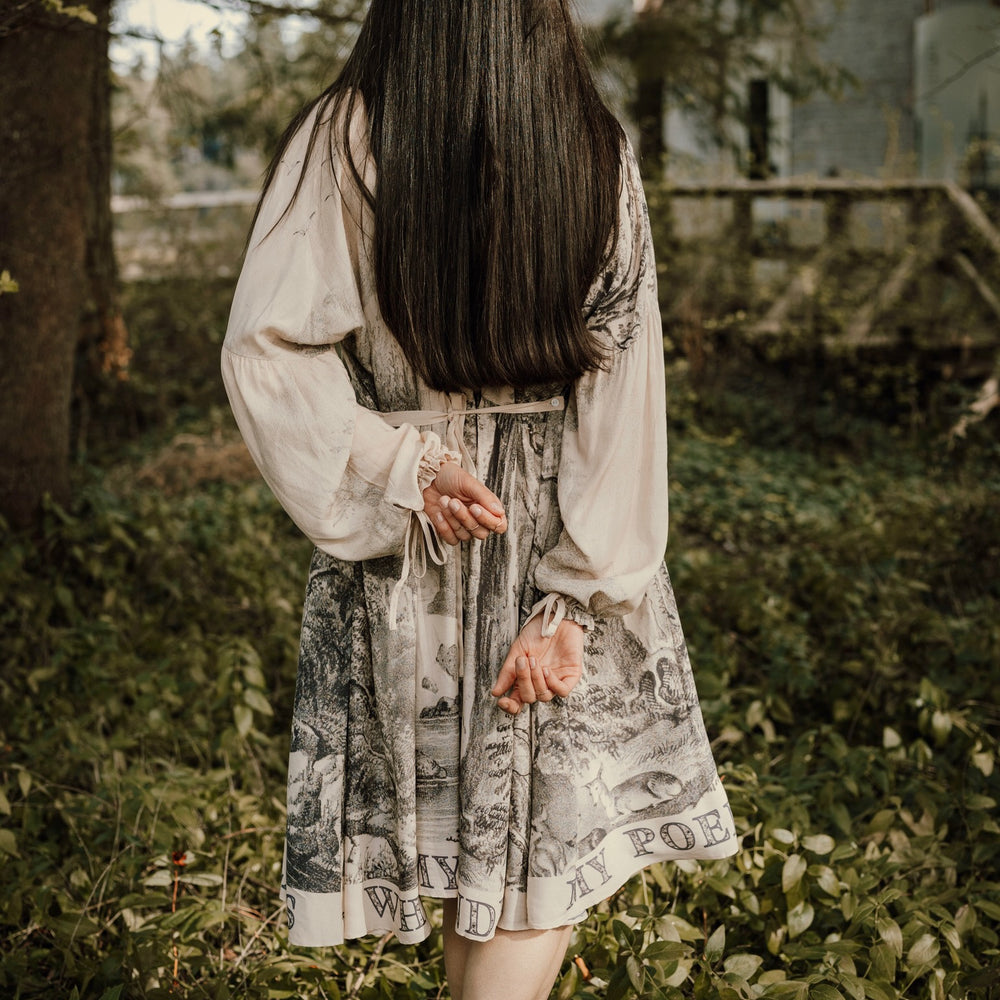 
                  
                    Model wearing knee-length dress with long sleeves featuring vintage print of a forest, songbirds and sunshine - Market of Stars
                  
                