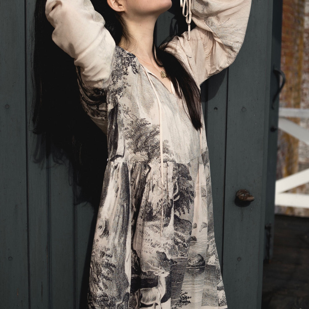 
                  
                    Model wearing knee-length dress with long sleeves featuring vintage print of a forest, songbirds and sunshine - Market of Stars
                  
                