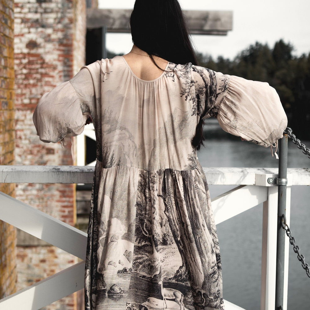
                  
                    Model wearing knee-length dress with long sleeves featuring vintage print of a forest, songbirds and sunshine - Market of Stars
                  
                