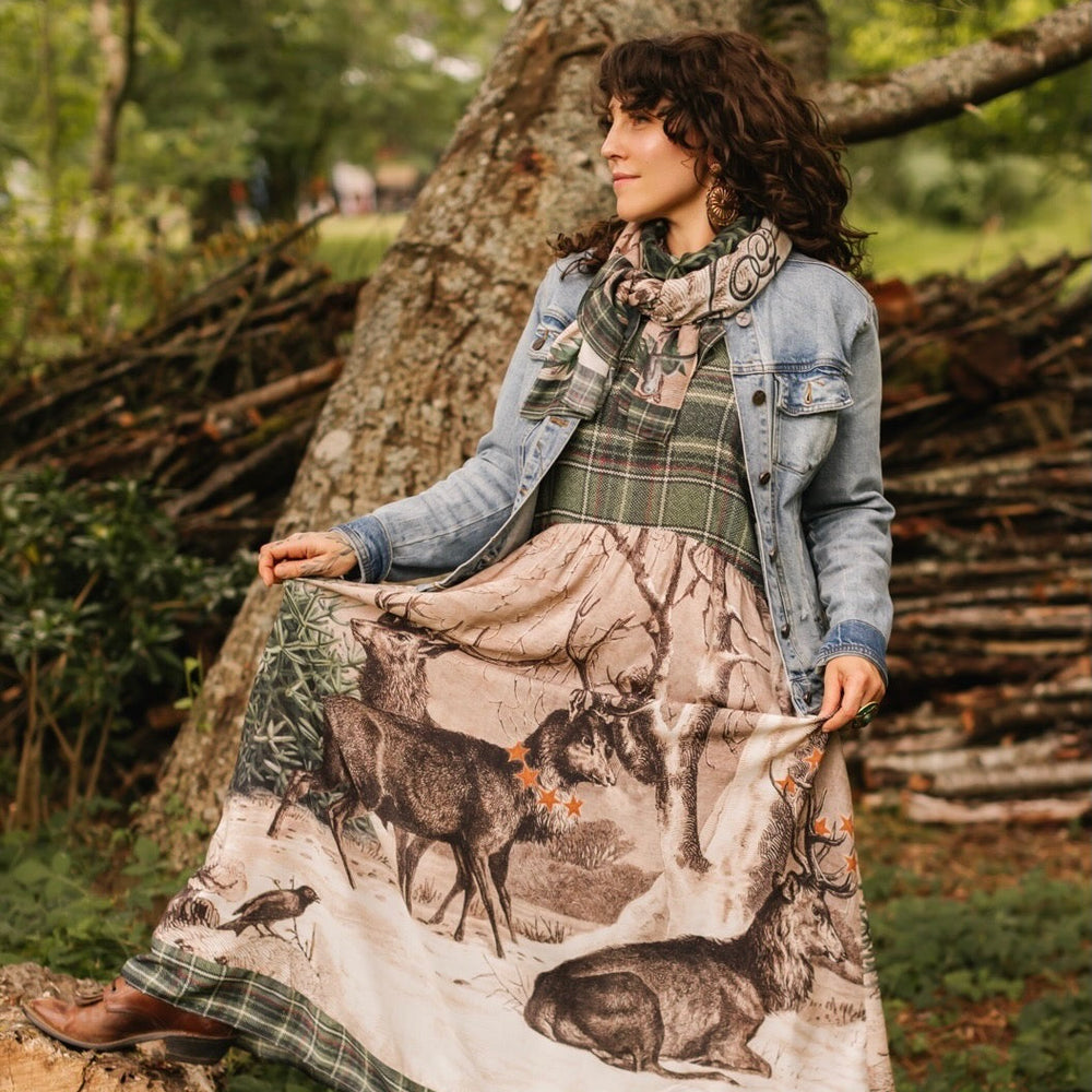 Model wearing a bamboo viscose maxi slip dress with Victorian-era images from holiday greeting cards — including reindeer in the snow, a little fir tree, golden stars, and traditional plaid trim - Market of Stars