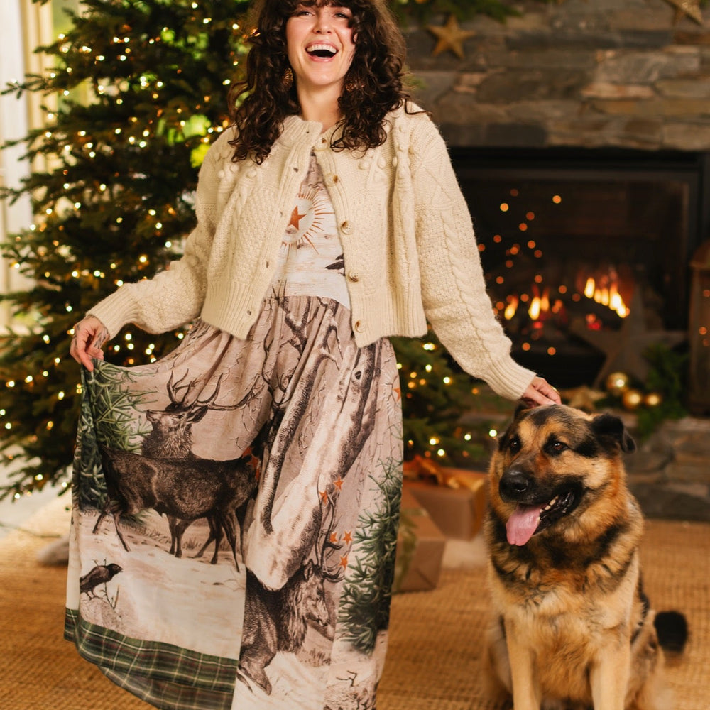 
                  
                    Model wearing a bamboo viscose maxi slip dress with Victorian-era images from holiday greeting cards — including reindeer in the snow, a little fir tree, golden stars, and traditional plaid trim - Market of Stars
                  
                