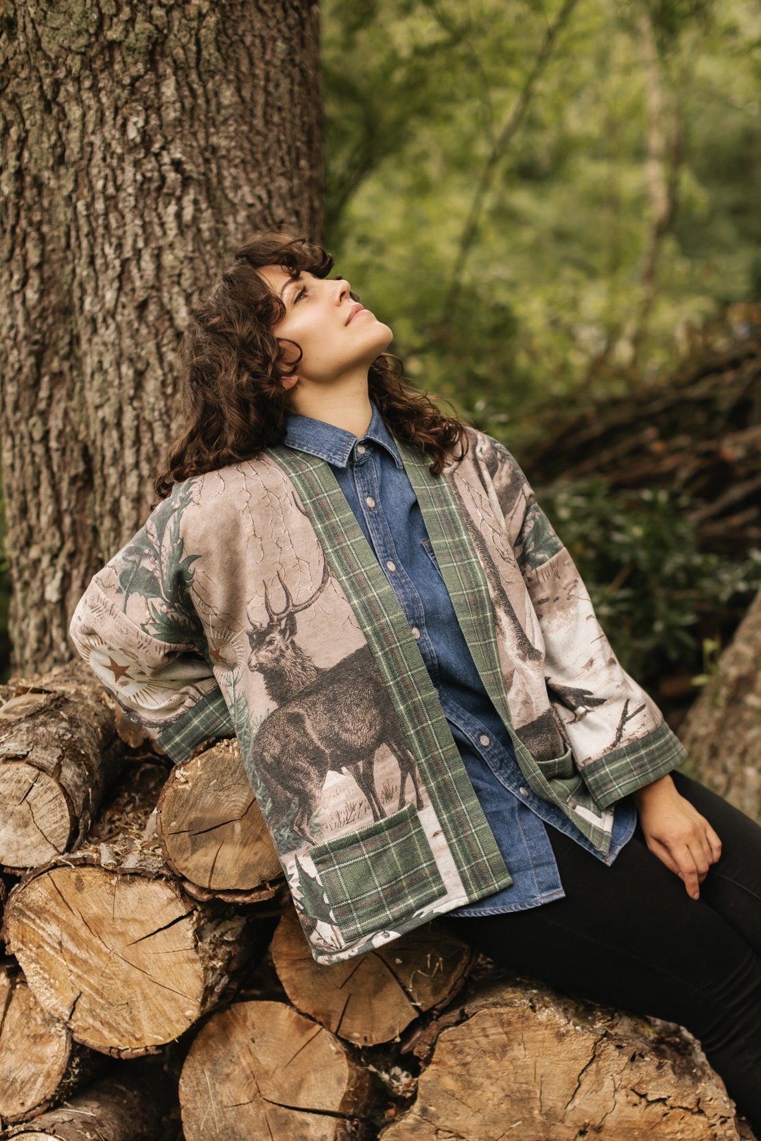 Model wearing a fleece lined jacket with pockets with Victorian-era images from holiday greeting cards — including reindeer in the snow, a little fir tree, golden stars, and traditional plaid trim - Market of Stars