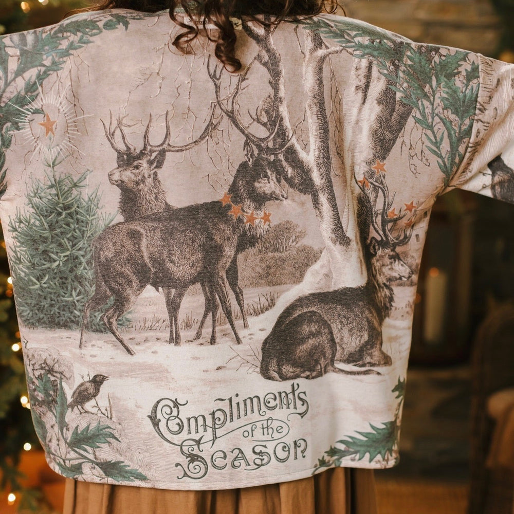 Model wearing a fleece lined jacket with pockets with Victorian-era images from holiday greeting cards — including reindeer in the snow, a little fir tree, golden stars, and traditional plaid trim - Market of Stars