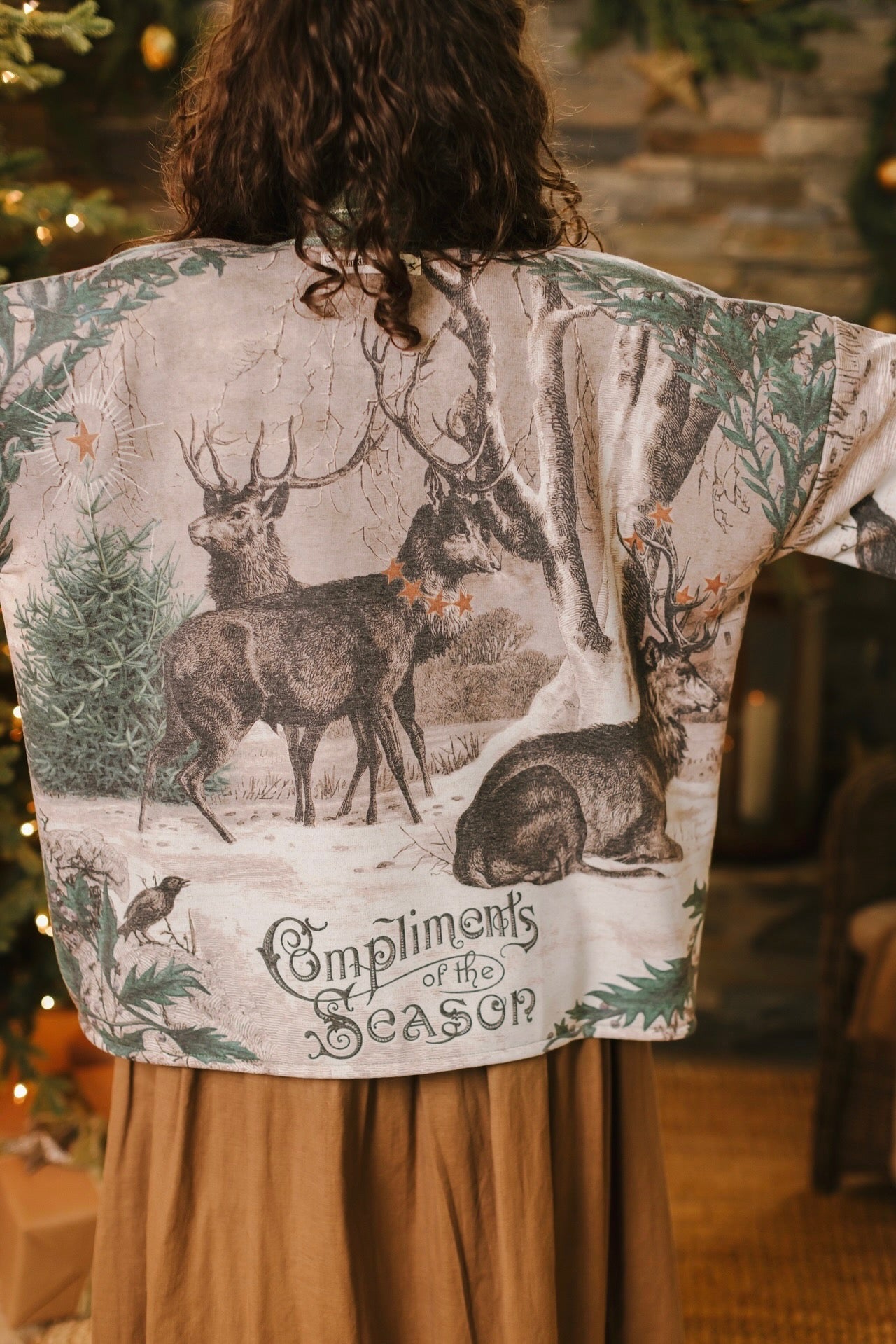 Model wearing a fleece lined jacket with pockets with Victorian-era images from holiday greeting cards — including reindeer in the snow, a little fir tree, golden stars, and traditional plaid trim - Market of Stars