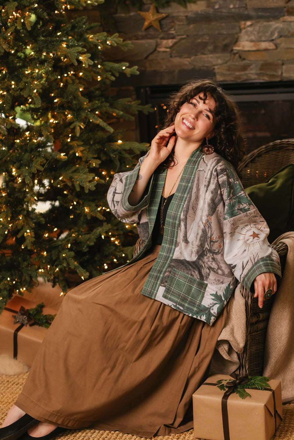Model wearing a fleece lined jacket with pockets with Victorian-era images from holiday greeting cards — including reindeer in the snow, a little fir tree, golden stars, and traditional plaid trim - Market of Stars