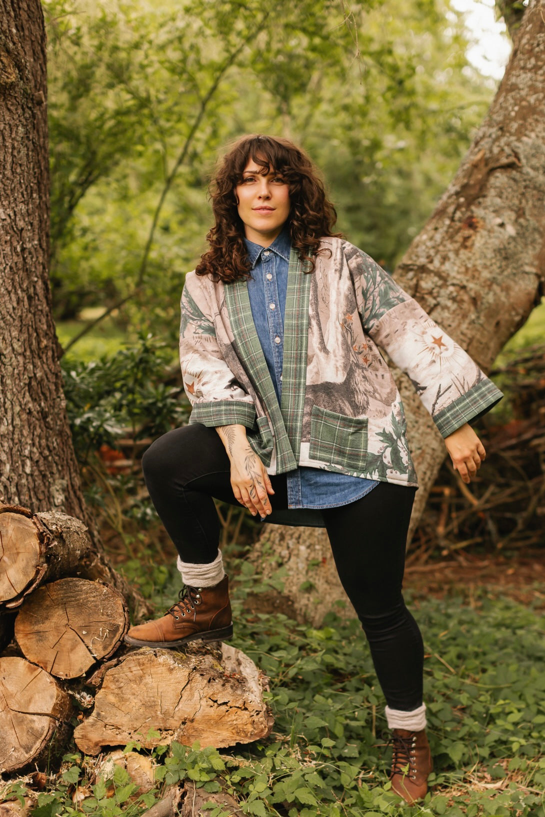 Model wearing a fleece lined jacket with pockets with Victorian-era images from holiday greeting cards — including reindeer in the snow, a little fir tree, golden stars, and traditional plaid trim - Market of Stars