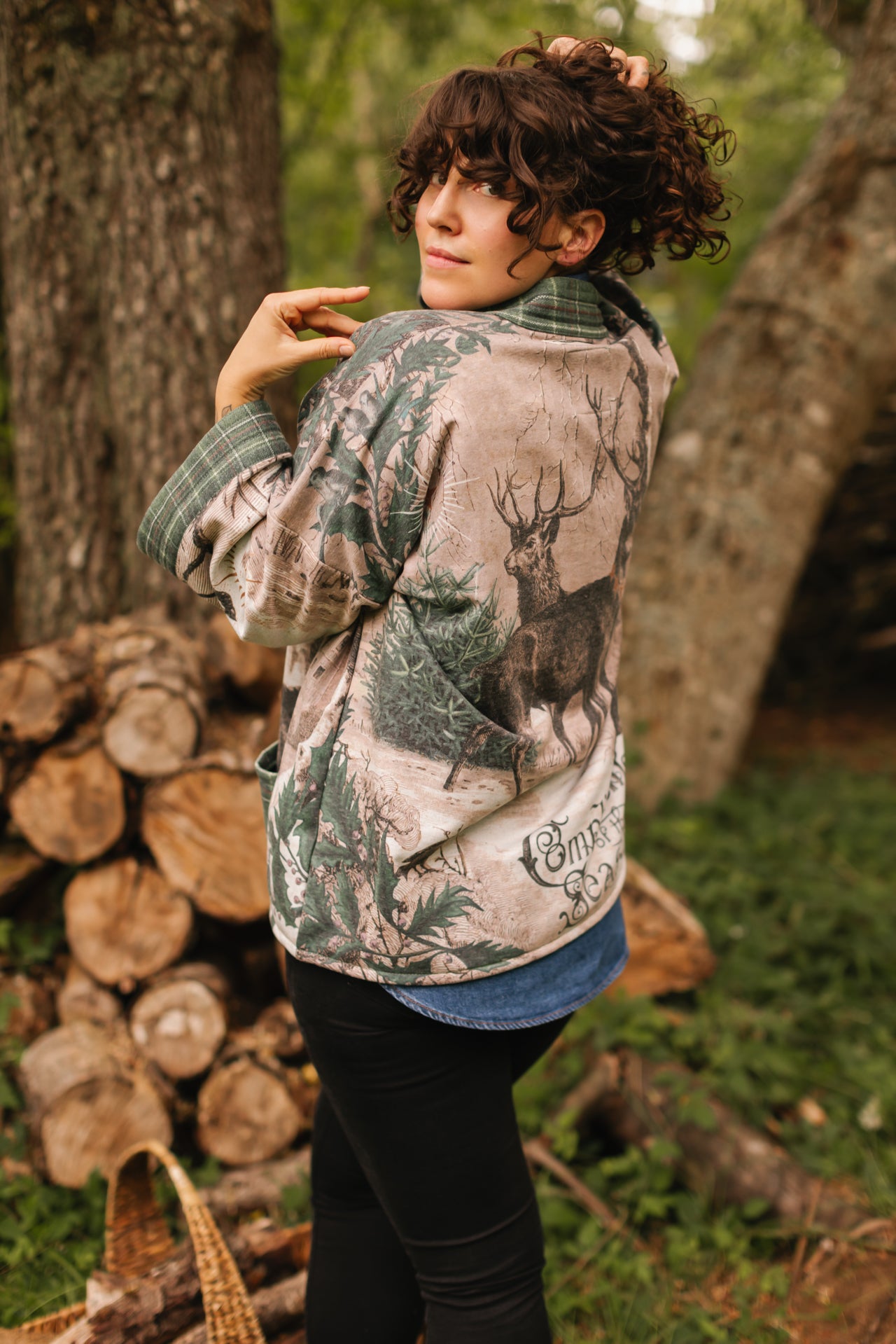 Model wearing a fleece lined jacket with pockets with Victorian-era images from holiday greeting cards — including reindeer in the snow, a little fir tree, golden stars, and traditional plaid trim - Market of Stars