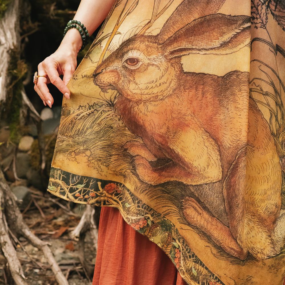 
                  
                    Model wearing a bamboo-viscose scarf where a noble rabbit rests deep within an underground burrow, surrounded by the warmth and safety of the earth. Created in collaboration with Charles van Sandwyck - Market of Stars
                  
                