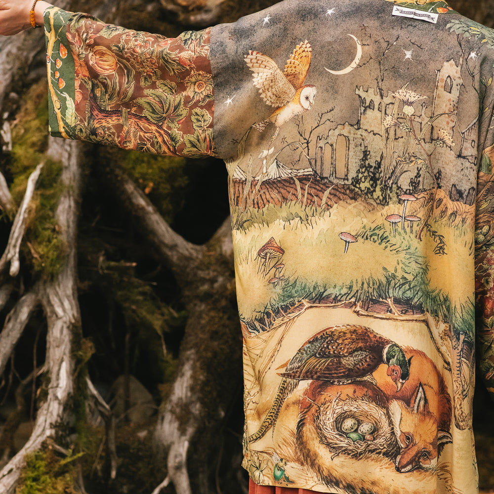 Model wearing a bamboo-viscose mid-length duster kimono robe where even the unlikeliest of friends...a fox and a pheasant...find warmth in each other’s company. Created in collaboration with Charles van Sandwyck - Market of Stars